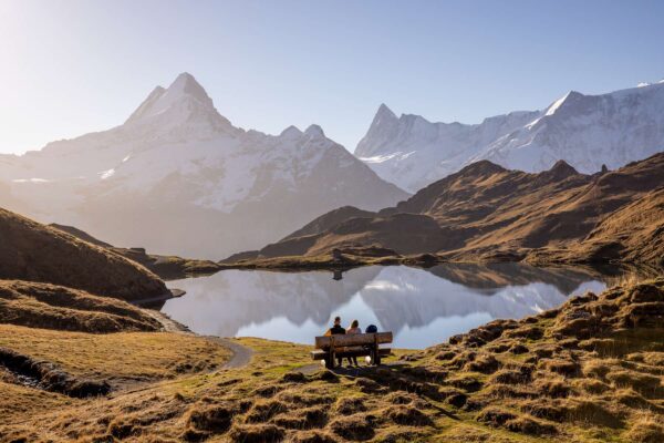 Três pessoas em banco diante do lago Bachalpsee, no Grindelwald First